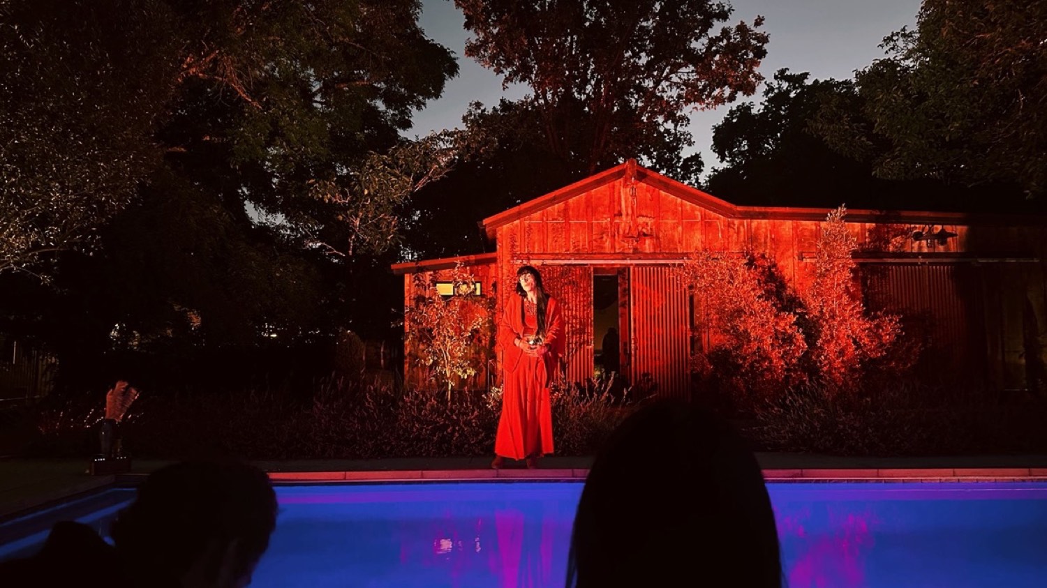 A seeker in red before a lit barn at Edge Esmeralda