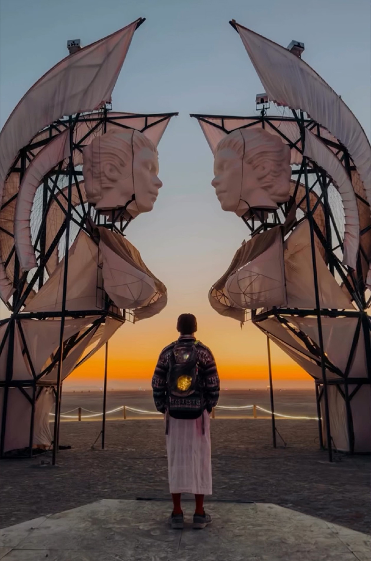 A seeker stands before the two sphinxes at sunset, Burning Man 2025